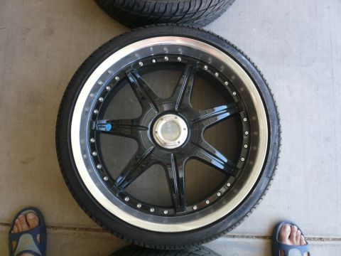 1996 Ford Probe - A black aftermarket wheel with a silver lip and five split spokes is shown, with two tires stacked behind it.
