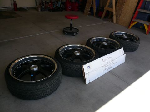 1996 Ford Probe - Four aftermarket wheels and tires are laid out on a garage floor next to a cardboard box.