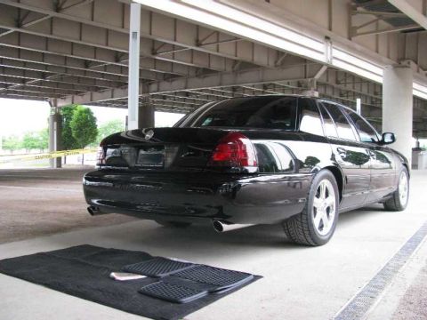 2003 Mercury Marauder - A black 2003 Mercury Marauder is shown from the rear, parked beneath an elevated structure with caution tape visible in the background.