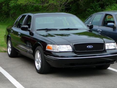 1997 Mercury Grand Marquis - A black sedan with a Ford grille is parked in a lot, with another vehicle beside it.