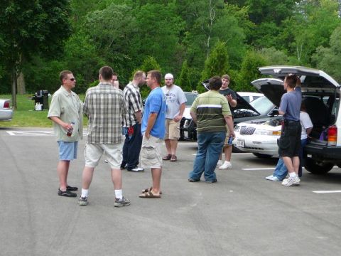 1997 Mercury Grand Marquis - A group of people gather around a 1997 Mercury Grand Marquis with its hood open at a car meet.