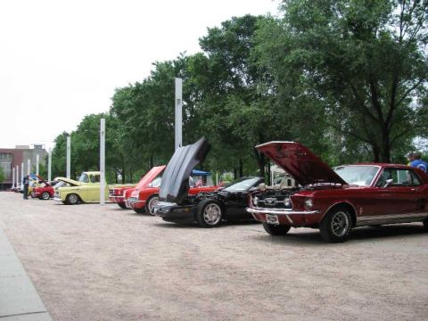 2003 Mercury Marauder - A red 1967 Ford Mustang coupe is displayed with its hood open at a car show, alongside other classic vehicles.