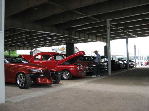 2003 Mercury Marauder - A collection of red cars are displayed under a covered area, with a man observing them.