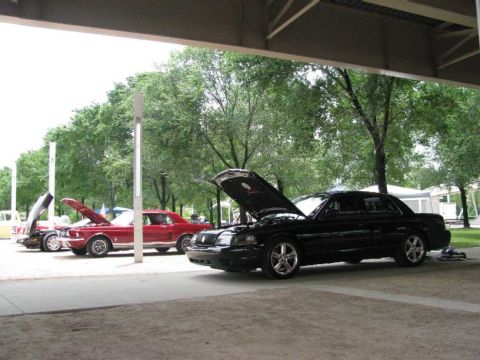2003 Mercury Marauder - A black 2003 Mercury Marauder is parked with its hood open, alongside other vehicles under an overhang.