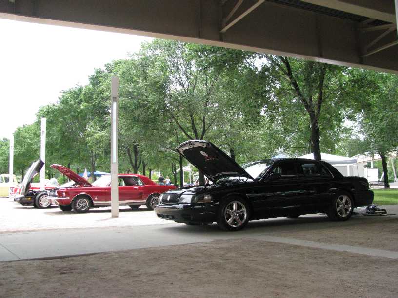 Black 2003 Mercury Marauder parked under cover with hood up, next to a red classic car