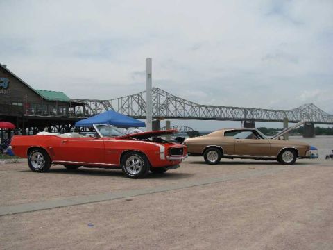 2003 Mercury Marauder - Two vintage cars are displayed outdoors with a bridge and waterfront building visible.