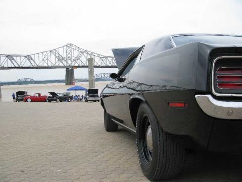 2003 Mercury Marauder - A black muscle car is parked near a river with a bridge in the background, alongside other vehicles.