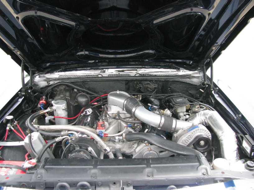 Modified engine bay with turbocharger and custom intake piping.