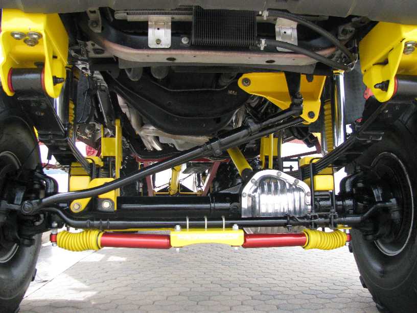 Underside of a custom vehicle with yellow suspension components and shiny differential cover.