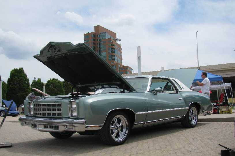Light green coupe with hood open, parked outdoors.