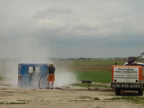 1992 Ford Bronco - Photograph of outdoor sandblasting work with a portable media-blasting trailer, not a technical document.