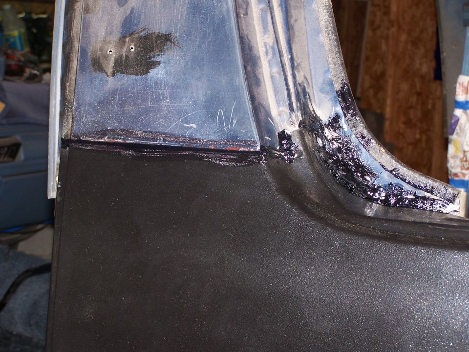 Close-up of vehicle body panel with black sealant applied along a seam.
