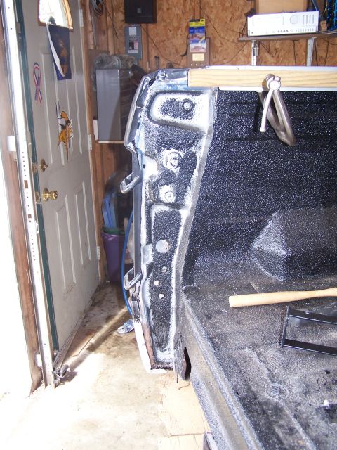 1986 Ford Bronco - A close-up view of the bed of a pickup truck, showing the inner fender well and the textured spray-in bed liner. A wooden brace is clamped…