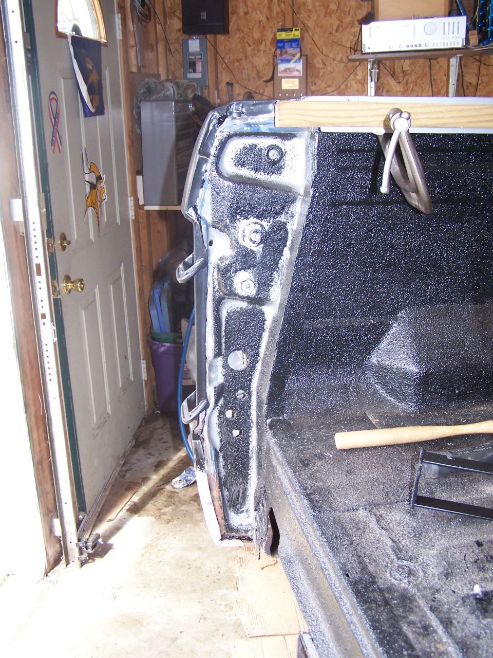 Close-up of pickup truck bed with spray-in liner and wooden brace.