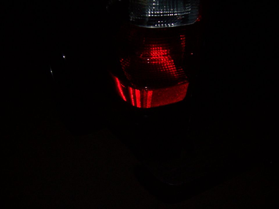Illuminated red vehicle tail light photographed in the dark