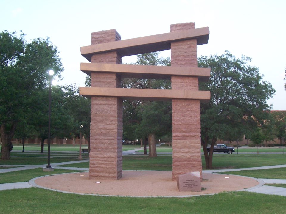 Large outdoor stone gateway sculpture on a campus lawn