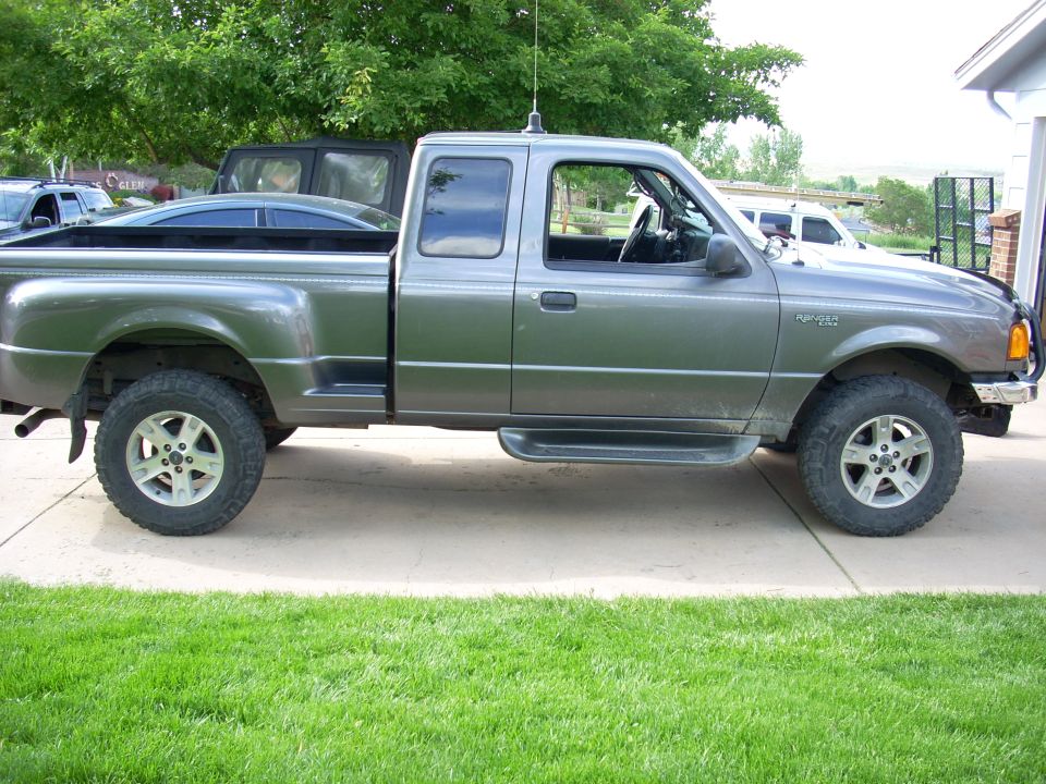 Side view of lifted gray Ford Ranger extended cab pickup with off-road tires on a driveway