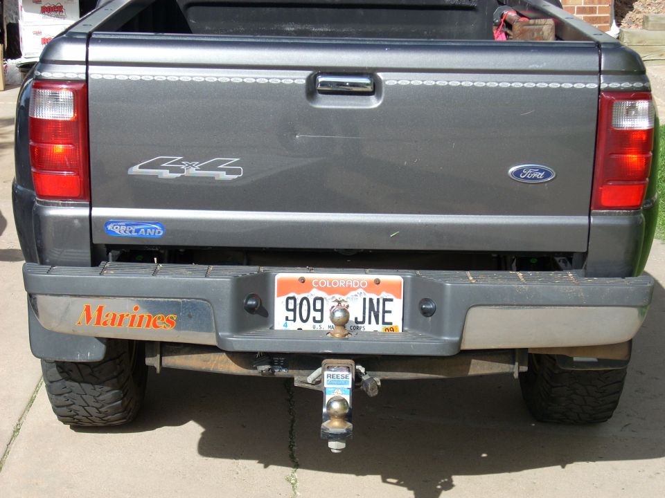 Rear of dark gray Ford 4x4 pickup with Marines bumper sticker, Colorado plate, and Reese trailer hitch