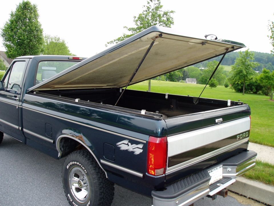 Dark green Ford pickup truck with open bed cover, chrome accents, and 4x4 decal.