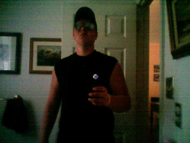 Person in a black cap and sunglasses taking a selfie.