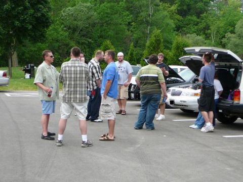 1997 Mercury Grand Marquis - A group of people are gathered around a white SUV in an outdoor setting.