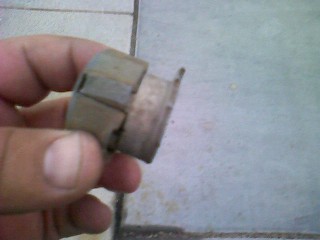 1965 Ford Ranchero - A hand holds a metal and plastic automotive part, possibly a connector or housing, against a tiled floor background.