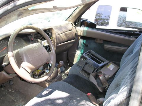 1986 Toyota Hilux - The interior of a Toyota truck shows a worn dashboard, steering wheel, and seats, with the center console removed.