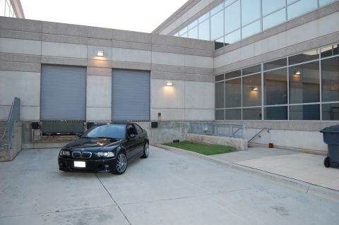 2002 BMW M3 - A black 2002 BMW M3 is captured in a three-quarter front view, parked outside a commercial building.