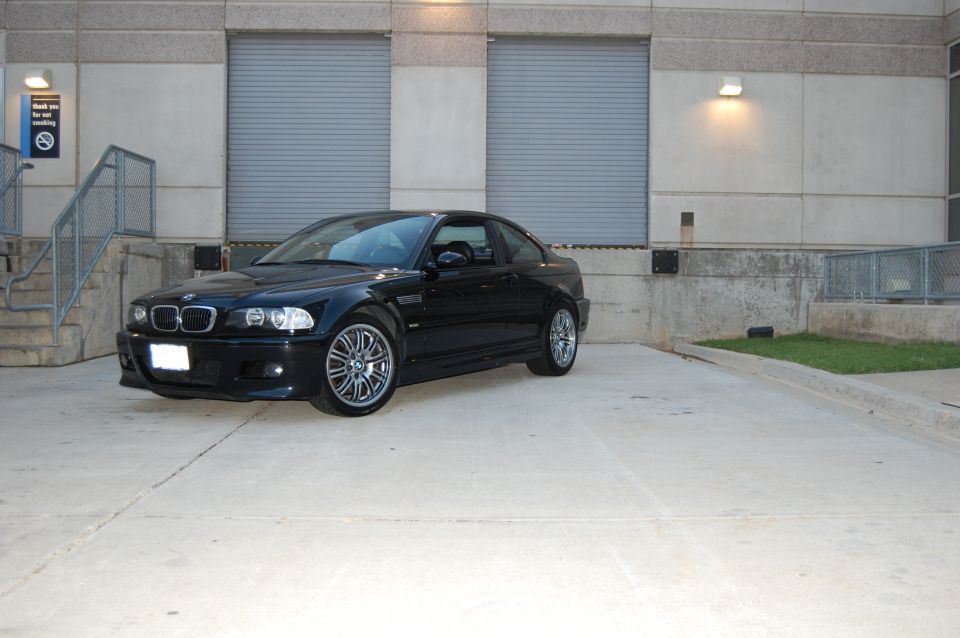 Black BMW M3 parked in front of a building with garage doors