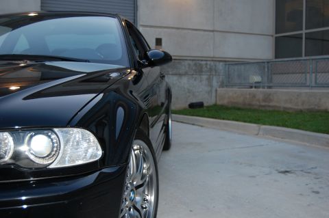 2002 BMW M3 - Close-up view of the front quarter panel and headlight of a black BMW M3.