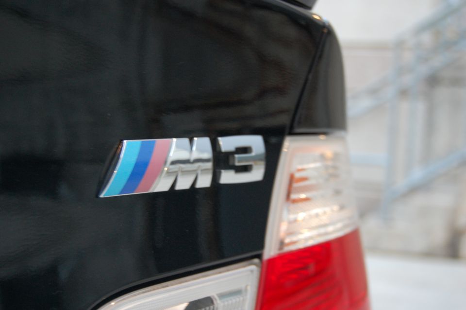 Black BMW M3 with tri-color stripe badge and taillight