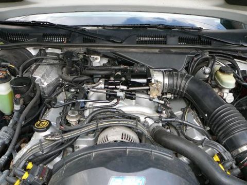 1997 Mercury Grand Marquis - A close-up view of the engine bay of a 1997 Mercury Grand Marquis, showing the intake manifold, air intake system, and various hoses and wi…