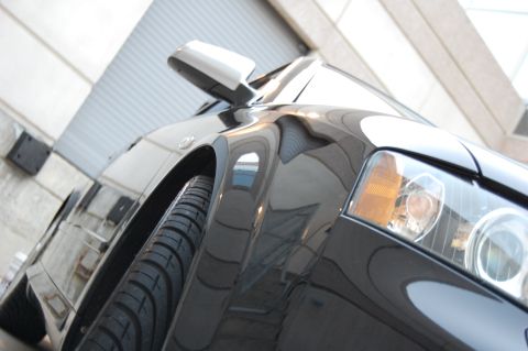 2002 BMW M3 - A black car's front quarter panel and headlight are visible from a low angle.
