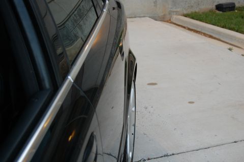 2002 BMW M3 - A black car is seen from the side, a chrome trim piece along the door and a glimpse of an alloy wheel.