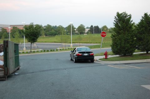 2002 BMW M3 - Black BMW M3 seen from the rear, turning at an intersection with a stop sign.