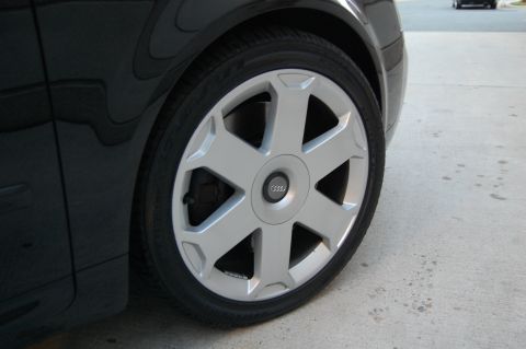 2002 BMW M3 - A close-up view of a silver Audi wheel and a portion of the black fender. Another vehicle is visible in the background.