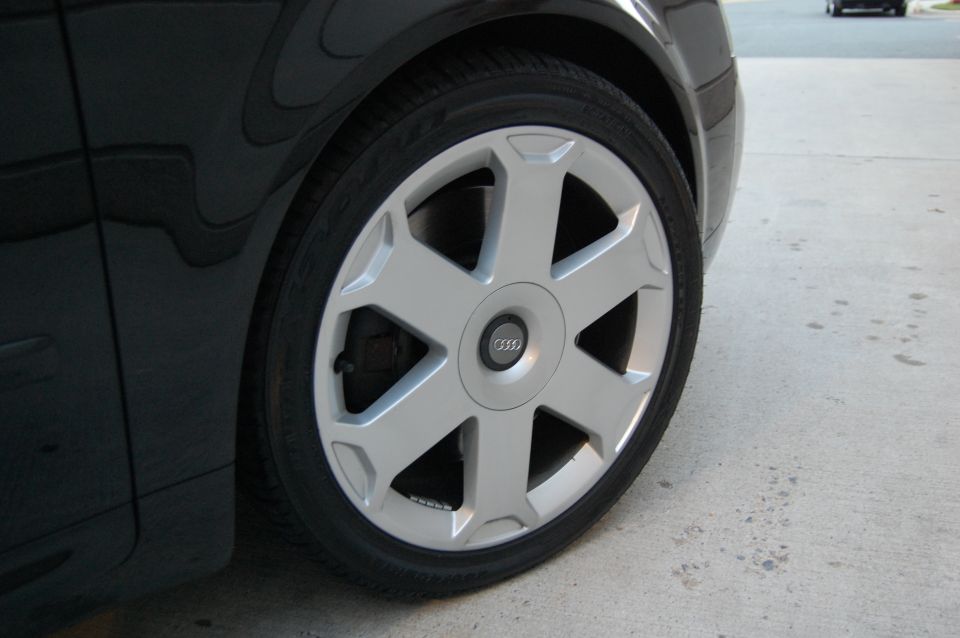 Close-up of a silver Audi wheel with a black tire and part of a black fender