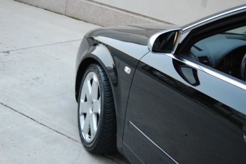 2002 BMW M3 - The front quarter panel and wheel of a black sedan are visible in this close-up shot.