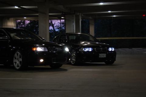 2002 BMW M3 - Two black sedans, a BMW M3 and an Audi S4, are parked in a garage at night.