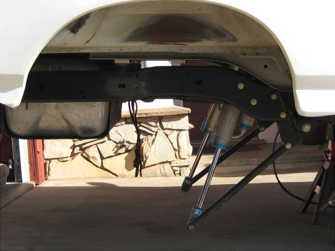 1996 Ford Bronco - Close-up view of the rear suspension system of a white vehicle, showing shock absorbers and fuel tank.