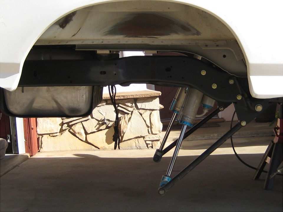 White vehicle's rear suspension with dual shocks and fuel tank visible