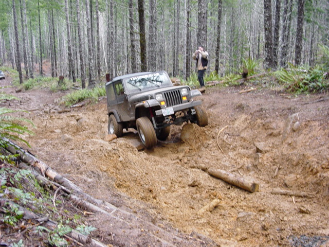 Jeep Wrangler stuck in deep mud on a forest trail with a photographer