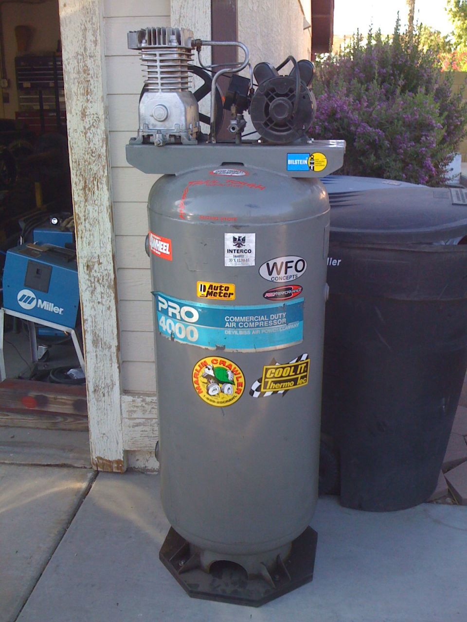 Gray vertical air compressor with 'PRO 4000 COMMERCIAL DUTY AIR COMPRESSOR' label and various stickers