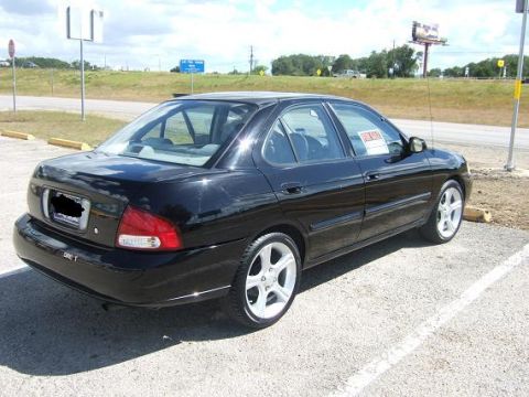 2000 Nissan Sentra - A black 2000 Nissan Sentra sedan is parked outdoors under a cloudy sky.