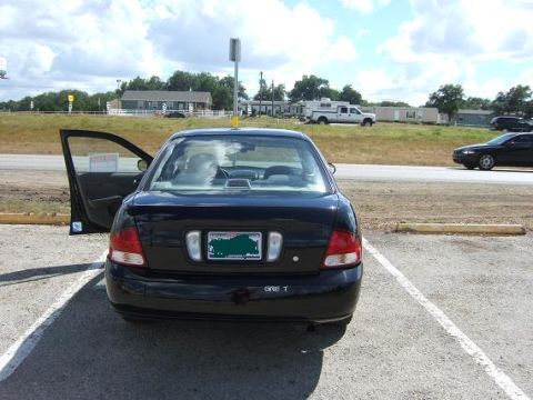 2000 Nissan Sentra - Rear view of a black sedan parked in a lot, with the driver's door ajar. The vehicle appears to be a 2000 Nissan Sentra.