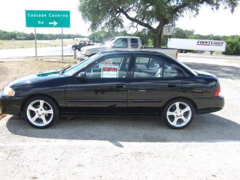 2000 Nissan Sentra - A black sedan is parked on the side of the road, with a "FOR SALE" sign in the window.