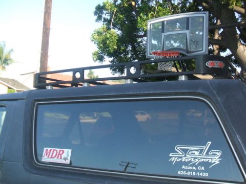 1988 Ford Bronco - This SUV has a basketball hoop mounted on its roof rack, with various stickers on the rear window.