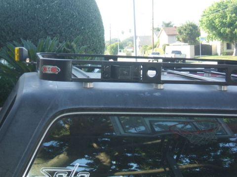 1988 Ford Bronco - A black roof rack is mounted on top of a dark SUV, with a basketball hoop reflected in the window.