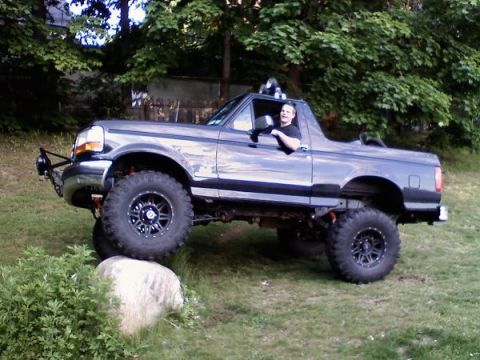 1995 Ford Bronco - A modified Ford Bronco navigates an obstacle on a grassy terrain.