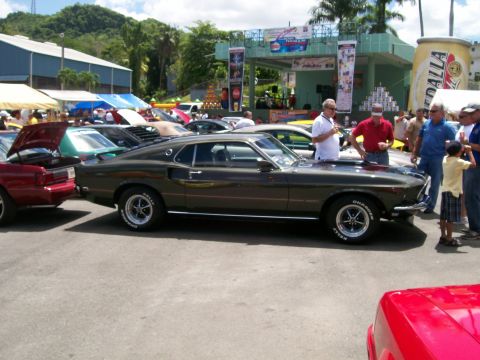 2001 Ford Mustang - A classic dark green Mustang Mach 1 is displayed at a car show with other vehicles and spectators.